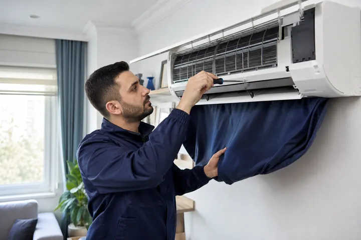 Markasız duvar tipi klimada teknik bakım yapan servis çalışanı